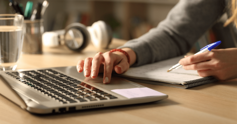 Close up of law student comparing notes on laptop sitting on a desk at home at night