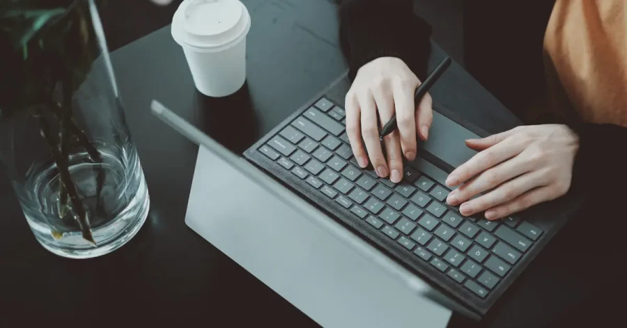 Student typing on a tablet keyboard with stylus in hand, preparing for the bar exam with Themis bar prep course, accompanied by coffee and study materials.
