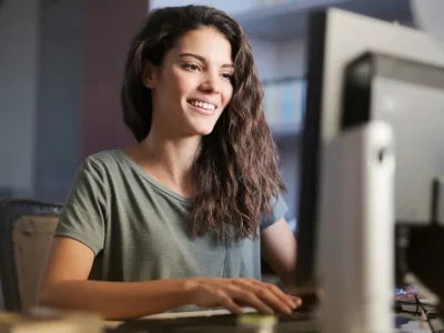 Smiling young woman studying for the bar exam online using Themis Bar Review course on a desktop computer in a home office environment.
