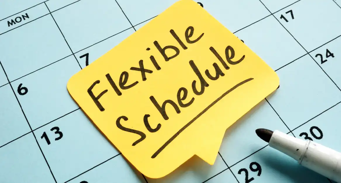 Yellow sticky note with the words "Flexible Schedule" placed on a calendar, next to a black marker.