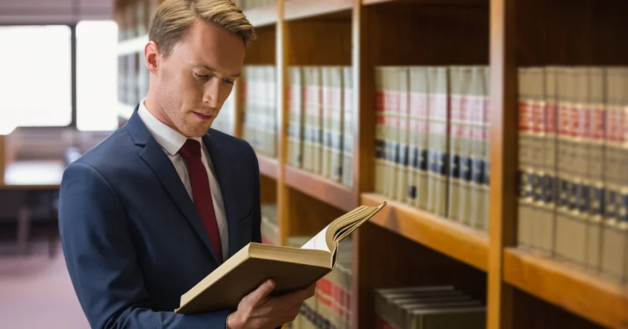 A determined man in a suit reviewing a law book in a library—symbolizing focused preparation for retaking the bar exam